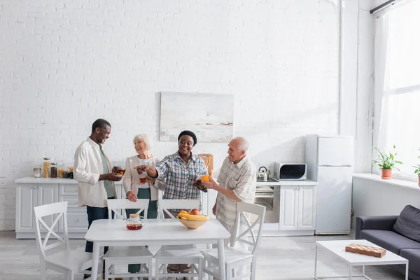 Позитивні міжрасові літні люди тримають чай і смартфон в будинку престарілих — стокове фото