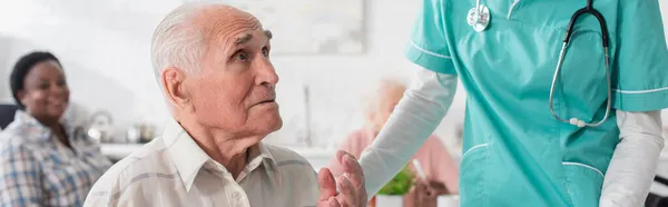 Uomo anziano che parla vicino all'infermiera nella casa di riposo, striscione — Foto stock