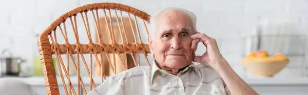 Homme âgé regardant la caméra dans une chaise berçante dans une maison de soins infirmiers, bannière — Photo de stock