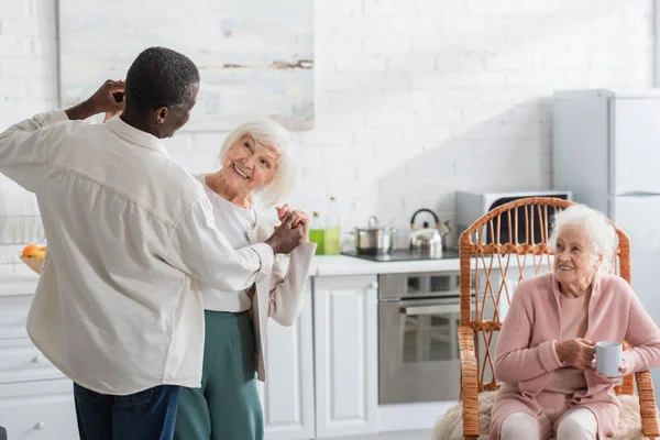 Старшая женщина танцует с африканским американским другом в доме престарелых — стоковое фото