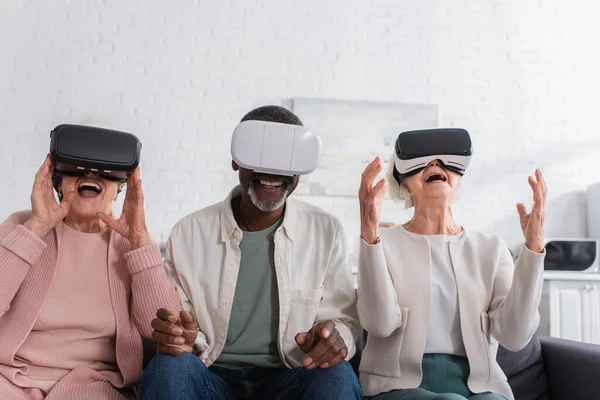 Cheerful interracial pensioners using vr headsets in nursing home — Stock Photo