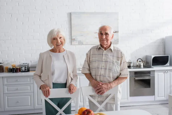 Des personnes âgées souriantes regardant la caméra dans la cuisine de la maison de soins infirmiers — Photo de stock