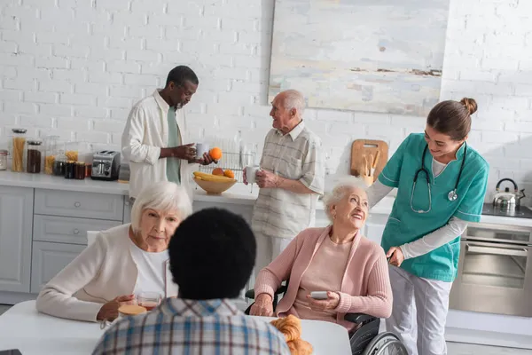 Мультиэтнические пожилые люди проводят время с медсестрой в доме престарелых — стоковое фото