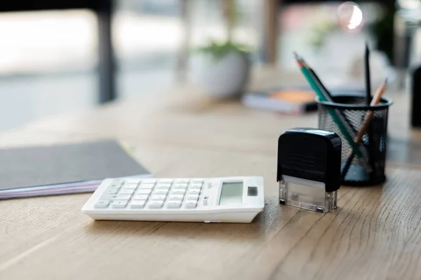 Calculator near paper folder and stamp in office — Stock Photo