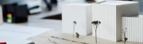 Modèle de bâtiment près de l'ordinateur portable sur la table de bureau, bannière — Photo de stock