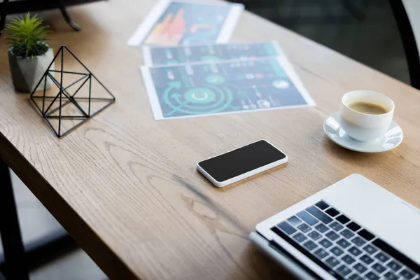 Visão de alto ângulo de dispositivos, café e papéis na mesa no escritório — Fotografia de Stock