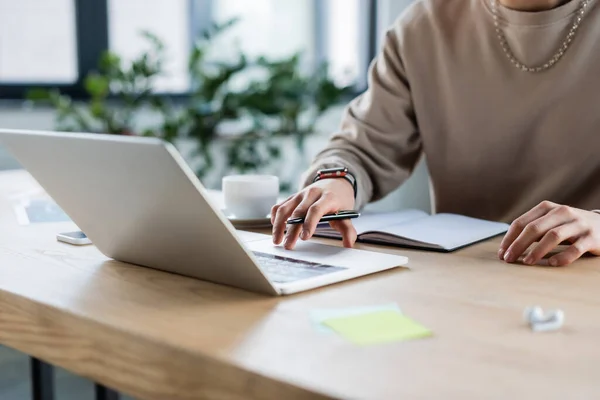 Vista ritagliata di uomo d'affari utilizzando laptop vicino notebook e caffè in ufficio — Foto stock