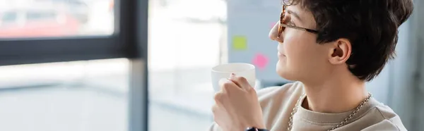 Vista lateral del hombre de negocios en gafas con taza en la oficina, pancarta - foto de stock