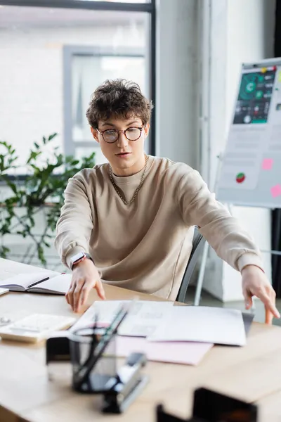 Joven hombre de negocios trabajando con documentos cerca de la calculadora en la oficina - foto de stock