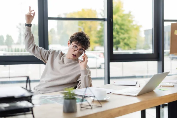 Businessman talking on cellphone near laptop and coffee in office — Stock Photo