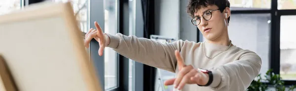 Businessman in earphone pointing at blurred board in office, banner — Stock Photo