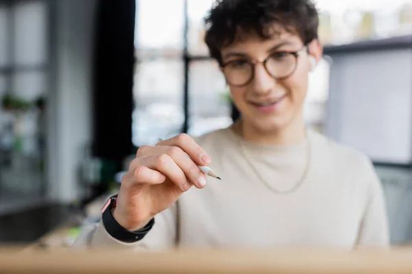 Pencil in hand of blurred businessman in office — Stock Photo