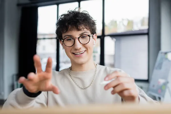 Smiling transgender person in earphones holding pencil in office — Stock Photo