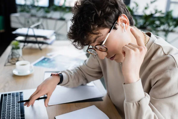 Uomo d'affari che indica auricolare vicino al computer portatile e notebook in ufficio — Foto stock