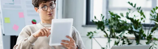 Businessman in earphones and eyeglasses using digital tablet in office, banner — Stock Photo