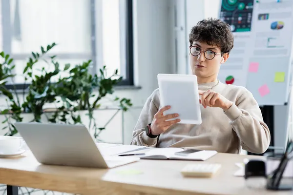 Бизнесмен, использующий цифровой планшет рядом с устройствами и кофе в офисе — стоковое фото