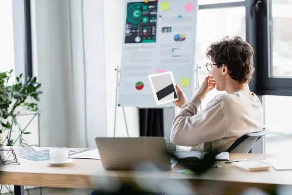 Geschockter Geschäftsmann mit digitalem Tablet in der Nähe von Laptop und Kaffee im Büro — Stockfoto