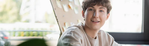 Positive transgender person looking at camera in office, banner — Stock Photo