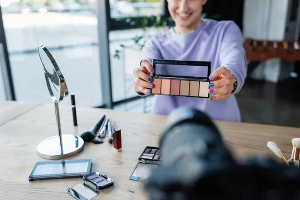 Cropped view of transgender person holding eye shadows near blurred digital camera — Stock Photo