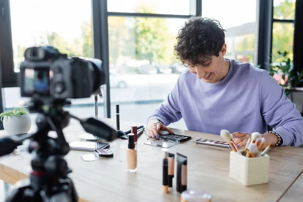Transgender pessoa olhando para cosméticos decorativos perto de câmera digital — Fotografia de Stock