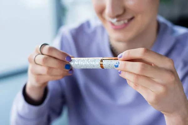 Cropped view of mascara in hands of blurred transgender person — Stock Photo