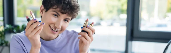 Sonriente persona transgénero sosteniendo pintalabios, pancarta - foto de stock