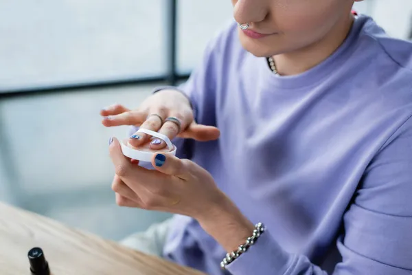 Cropped view of transgender person holding sponge and face powder in studio — Stock Photo