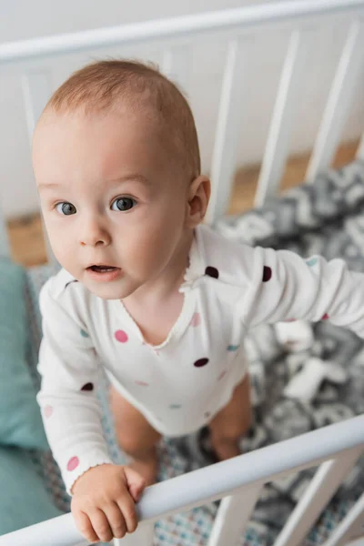 High angle view of little boy standing in crib at home — Stock Photo