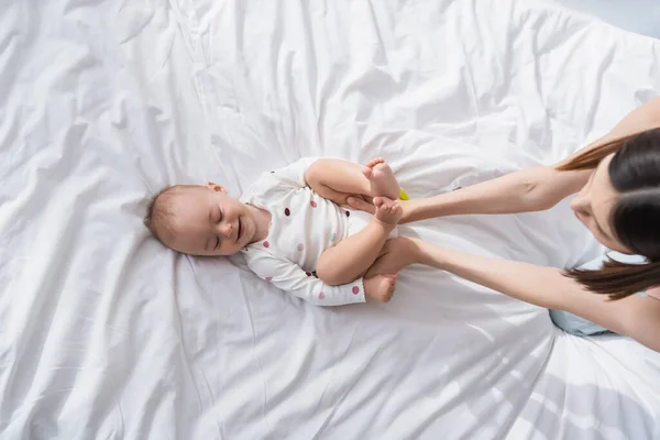 Ansicht von oben: Brünette Frau berührt lächelnden Sohn, der auf Bett liegt — Stockfoto