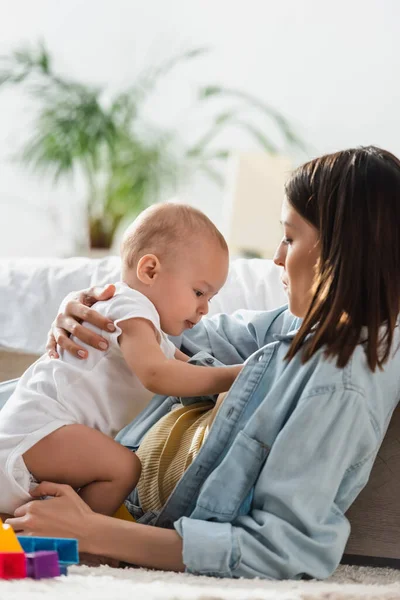 Brunette woman playing with toddler son on floor at home — Stock Photo