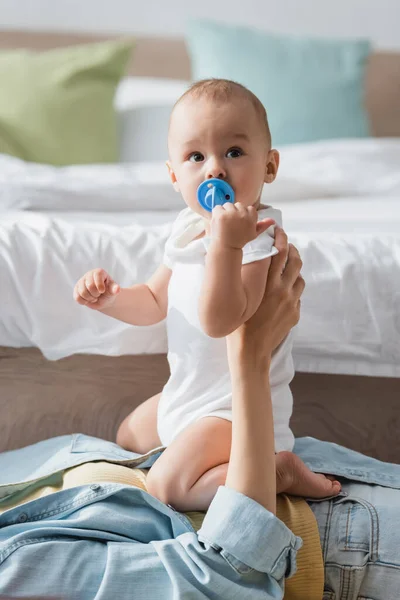 Toddler boy in romper sitting on mom lying on floor in bedroom — Stock Photo