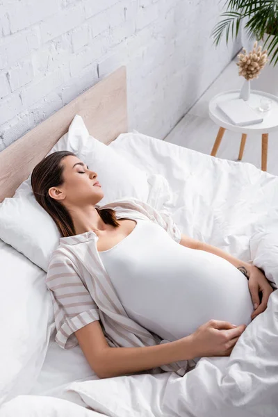 Vue grand angle de la femme enceinte en pyjama dormant au lit — Photo de stock