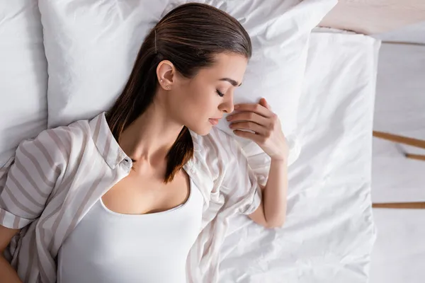 Вид сверху на спящую в постели молодую женщину в пижаме — стоковое фото