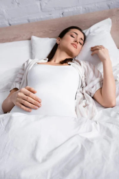 Jeune femme enceinte en pyjama dormant au lit — Photo de stock