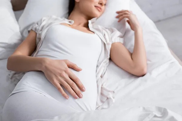 Ausgeschnittener Blick auf zufriedene Schwangere im Bett — Stockfoto