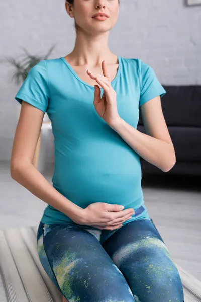 Обрізаний вид вагітної жінки жестикулює під час медитації вдома — стокове фото