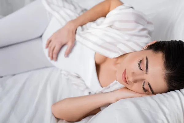 Mujer embarazada joven durmiendo en el dormitorio - foto de stock