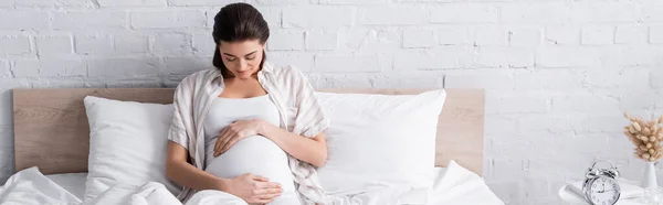 Pregnant young woman touching belly in bedroom, banner — Stock Photo