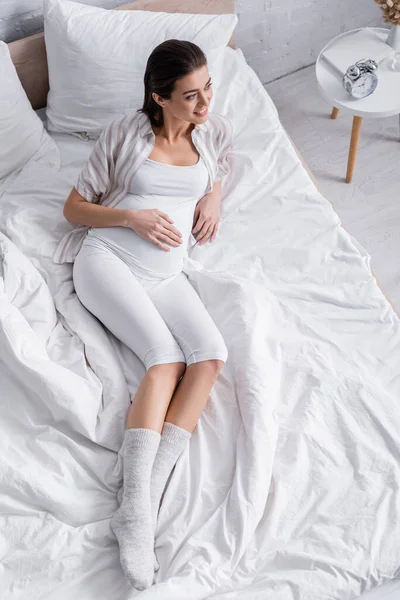 High angle view of smiling pregnant woman looking away in bedroom — Stock Photo