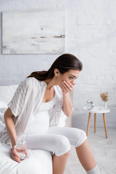 Pregnant woman feeling nausea and covering mouth — Stock Photo