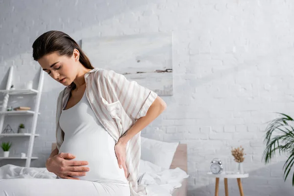 Mujer embarazada con los ojos cerrados sintiendo dolor abdominal - foto de stock