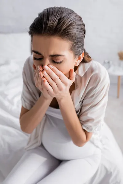 Jeune femme enceinte ayant des nausées et couvrant la bouche — Photo de stock