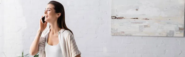 Sonriente mujer joven hablando en el teléfono inteligente en el dormitorio, pancarta - foto de stock