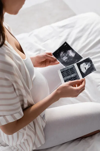 Partial view of pregnant woman holding ultrasound scans — Stock Photo