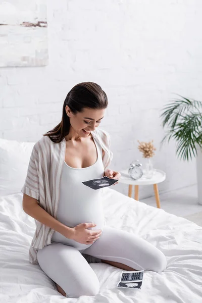 Mujer embarazada feliz sosteniendo ultrasonido escaneo - foto de stock