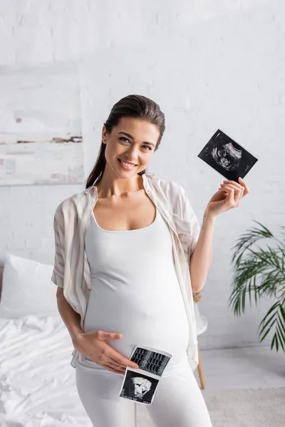 Positive and pregnant woman holding ultrasound scans — Stock Photo