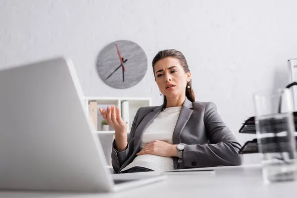 Mulher de negócios grávida descontente gesticulando durante videochamada no laptop — Fotografia de Stock