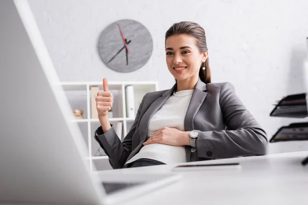 Heureux femme d'affaires enceinte montrant pouce vers le haut pendant l'appel vidéo sur ordinateur portable — Photo de stock