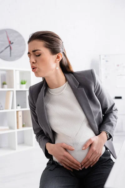 Donna d'affari incinta toccando pancia mentre si sente crampi — Foto stock