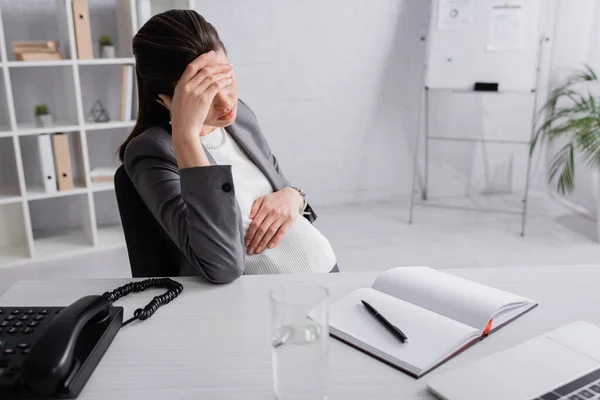 Pregnant businesswoman in suit feeling unwell in office — Stock Photo